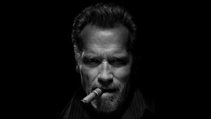 Arnold Schwarzenegger smokes a cigar in the dark